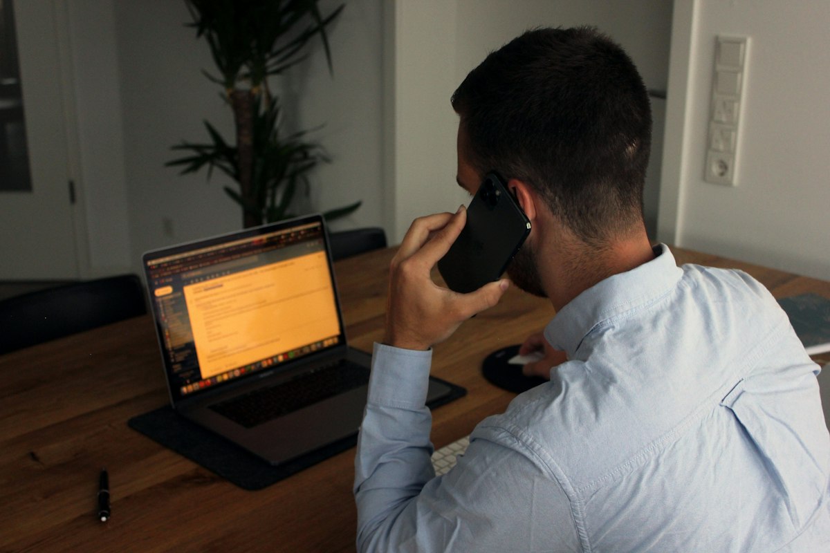 A professional on a phone call at his laptop in the evening