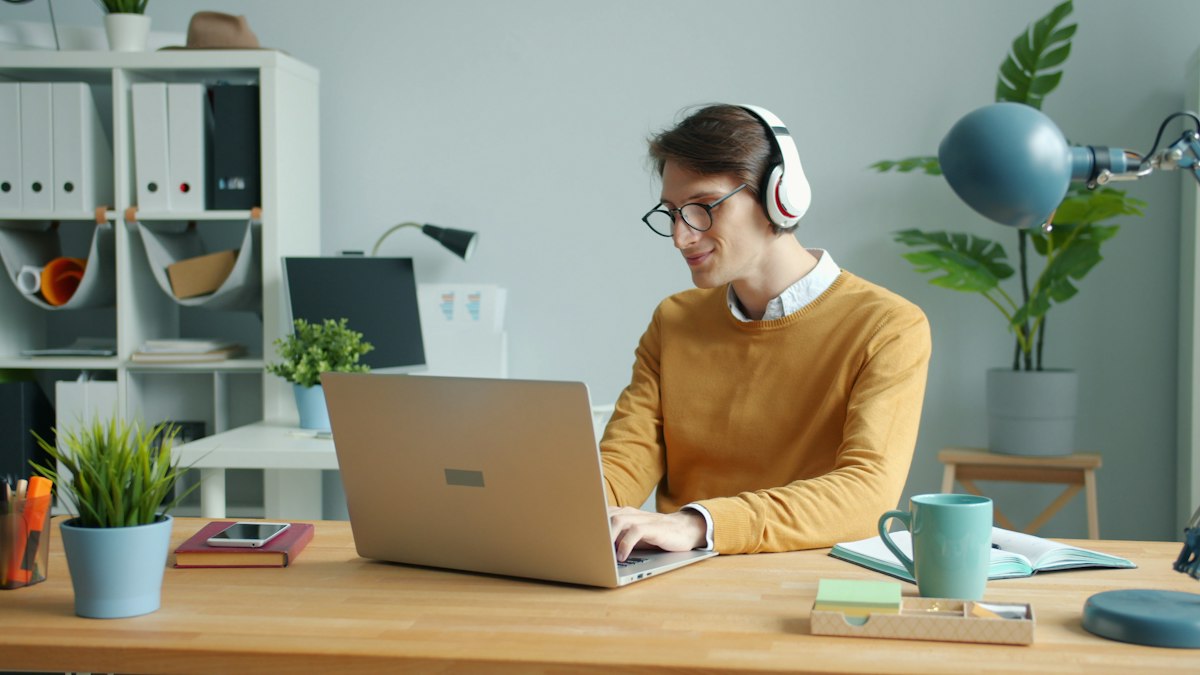 A professional in a headset on a call at his laptop