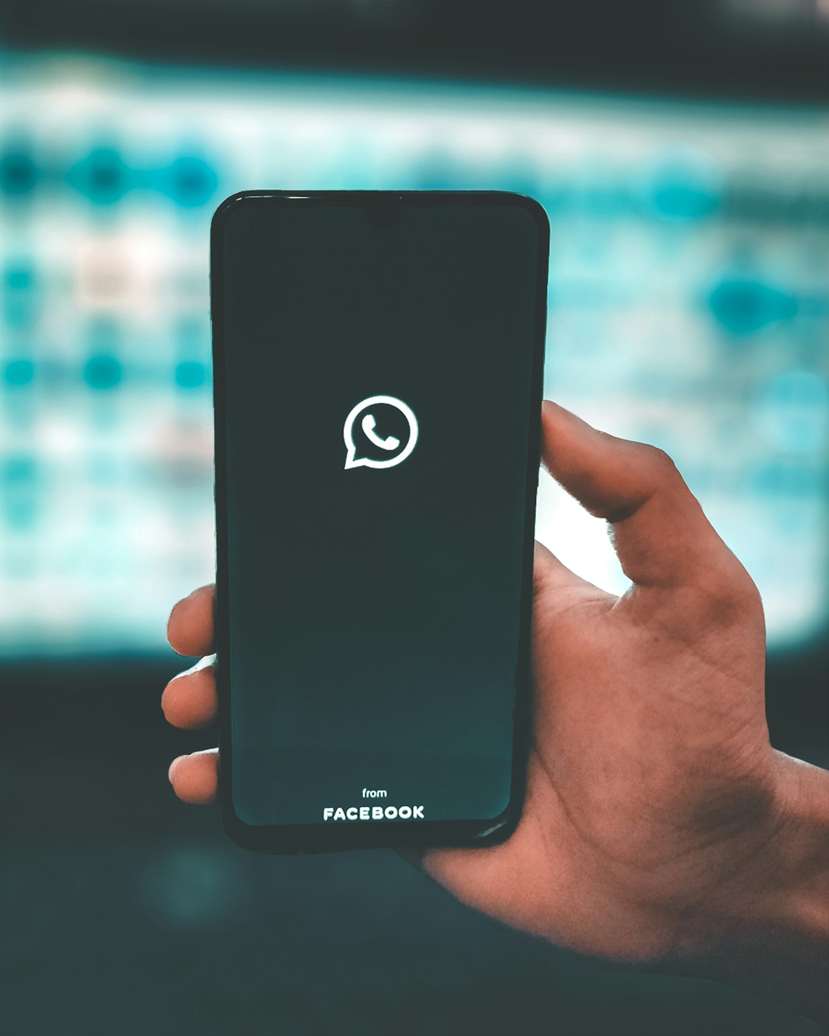 A hand holding a smartphone with WhatsApp opening on the screen